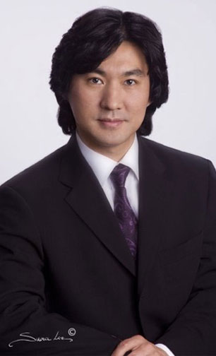 A man in a suit stands confidently against a white background.